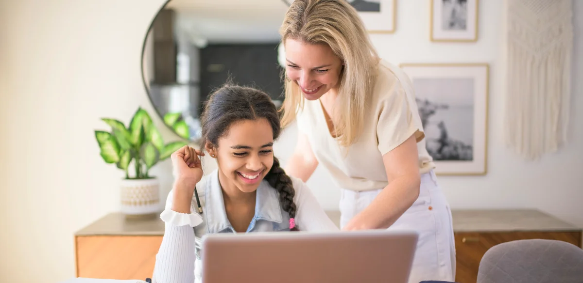 mom and girl smiling and looking the computer